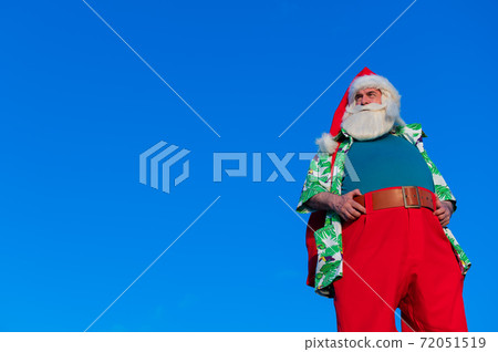 Santa claus in a hawaiian shirt on a blue background. Santa claus in a hawaiian shirt on a blue background. 72051519