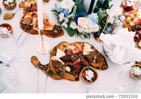 Cutting boards with cheese, prosciutto, and black bread on the festive table. 72051520