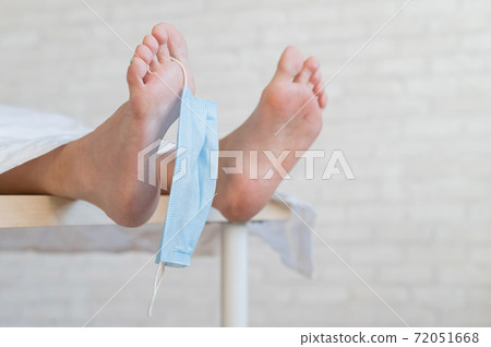 Close-up of dead men feet in a morgue with a medical mask on a toe. An unrecognizable woman has died from the coronavirus 72051668