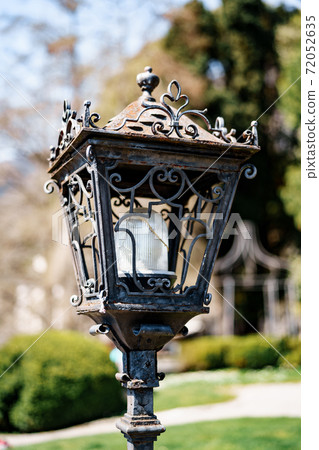 Close-up of a street lamp with a metal body with patterns in the park. Close-up of a street lamp with a metal body with patterns in the park. 72052635
