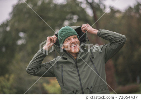 Young man in a green coat walking in the rain Young man in a green coat walking in the rain 72054437