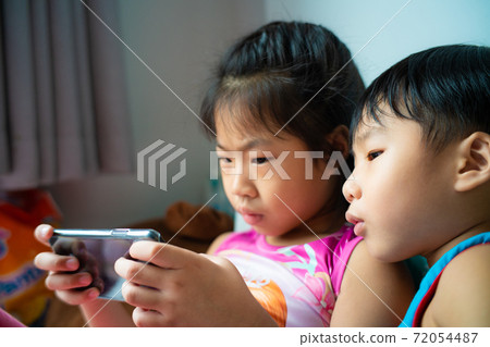 Brother and sister two kid playing internet game on mobile phone 72054487