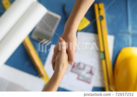 Handshake between designer and client over documents in studio closeup 72057252