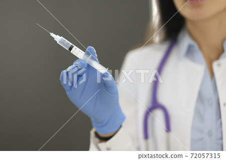 Doctor holding syringe with medicine in hand in rubber glove in clinic closeup 72057315