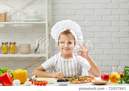 little boy in chef hat and an apron cooking pizza 72057841