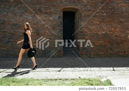 Elegant female model wearing walking near brick wall. Elegant female model wearing walking near brick wall. 72057953