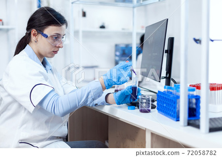 Young scientist loads pipette with sample for dna examination 72058782