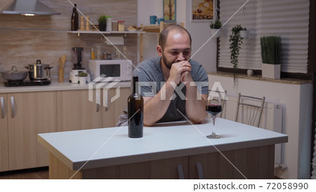 Sad husband drinking in the kitchen Sad husband drinking in the kitchen 72058990