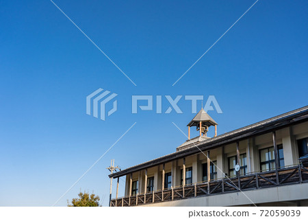 Bell on the roof of an old school, pointed roof Bell on the roof of an old school, pointed roof 72059039