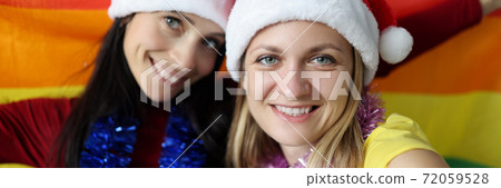 Two women in santa claus hats holding lgbt. 72059528