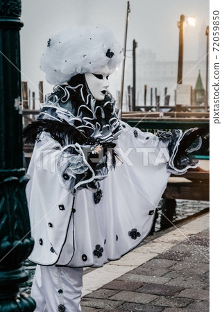 Person in Harlequin carnival costume on the background of the venetian lagoon Person in Harlequin carnival costume on the background of the venetian lagoon 72059850