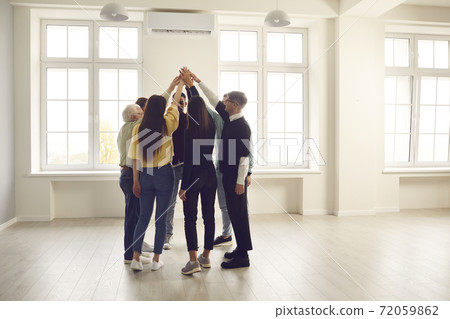 Group of diverse people standing in circle in office space and joining their hands Group of diverse people standing in circle in office space and joining their hands 72059862