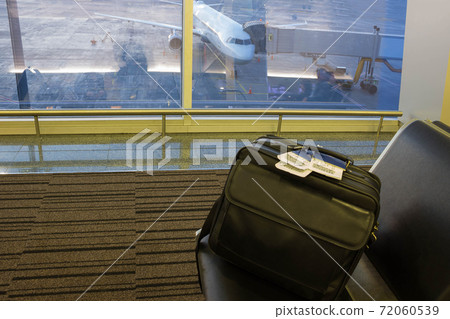 Suitcase in airport departure lounge, airplane in background, summer vacation concept 72060539