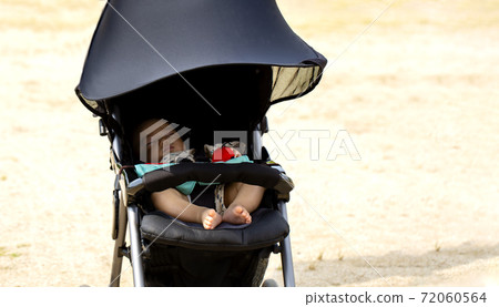 Copy space with baby sleeping in a black stroller in the park 72060564