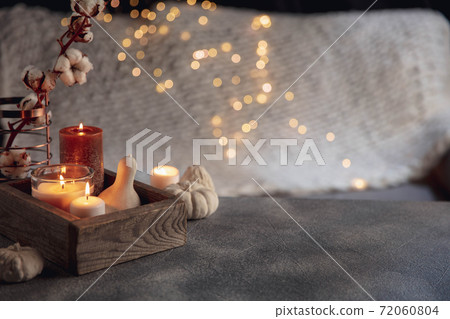 Burning candles in the wooden box isolated on grey and white background with garland lights. Greeting card design. 72060804