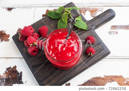 Homemade raspberry jam in a glass jar and fresh raspberries with mint on a wooden rustic background. Copy space Homemade raspberry jam in a glass jar and fresh raspberries with mint on a wooden rustic background. Copy space 72062238