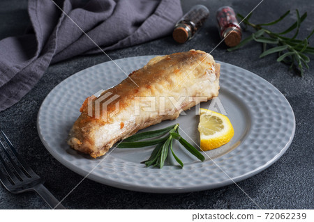 Fried fish hake Pollock and slices of fresh lemon. Dark concrete background. Copy space. Fried fish hake Pollock and slices of fresh lemon. Dark concrete background. Copy space. 72062239