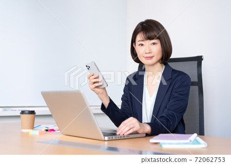 Middle-aged woman holding a smartphone in an office conference room Middle-aged woman holding a smartphone in an office conference room 72062753