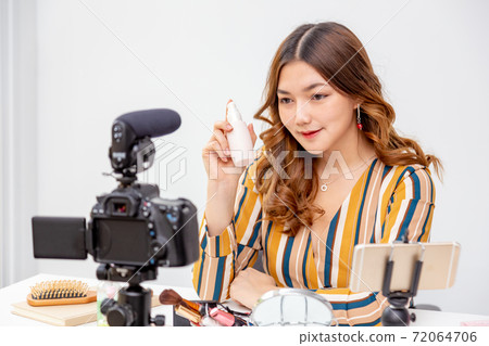 Beautiful young Asian woman making online product review at home Beautiful young Asian woman making online product review at home 72064706