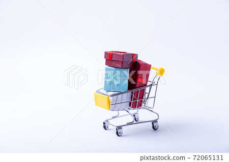 Miniature cart with gifts on a white background. Holidays shopping concept. Close-up. 72065131