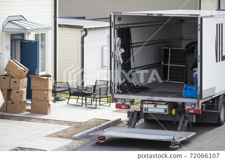 A moving truck is parked on the side of a building 72066107