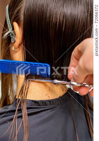 Hairdresser cuts hair of woman 72066372