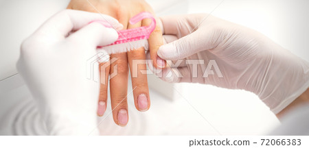 Manicurist cleans dust with brush Manicurist cleans dust with brush 72066383