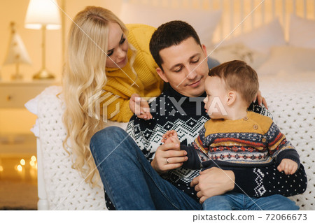 Young family spend time at home in Christmas time. Happy Mom, dad and son enjoyng love hugs, holidays people. Togetherness concept 72066673