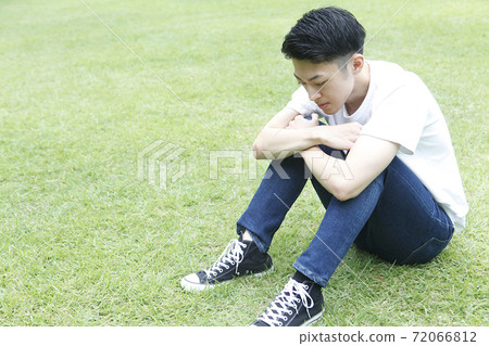 Profile of a young man sitting on the grass 72066812