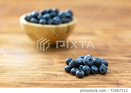 Pile of fresh blueberries laying on table with full bowl on background. 72067111