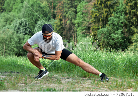 Bearded athletic man doing workout exercise in the outdoor gym in sunset Bearded athletic man doing workout exercise in the outdoor gym in sunset 72067113