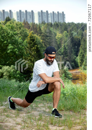 Bearded athletic man doing workout exercise in the outdoor gym in sunset 72067117