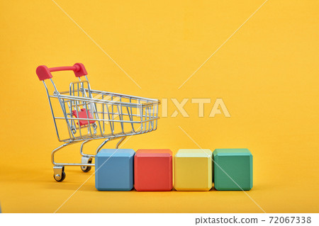 empty wooden cubes mockup style, copy space with shopping trolleys on yellow background. Colourful blocks template for creative design, place for text 72067338