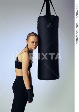 athletic woman in black boxing bandages leaning on punching bag athletic woman in black boxing bandages leaning on punching bag 72067652