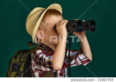 Little boy tourist with backpack looking through a binoculars. 72067704