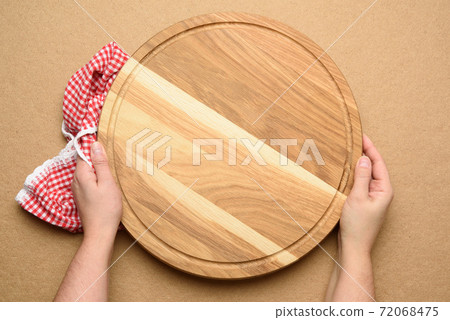 woman holding empty round wooden pizza board in hand woman holding empty round wooden pizza board in hand 72068475
