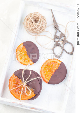 Homemade candied sliced oranges covered with chocolate on white tray, vertical, top view Homemade candied sliced oranges covered with chocolate on white tray, vertical, top view 72068784