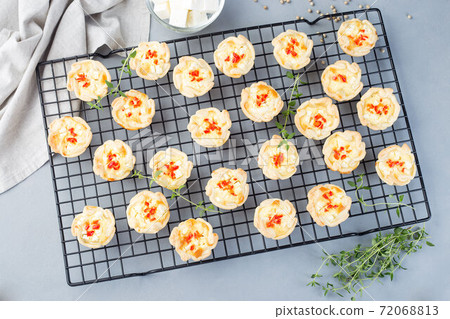 Mini quiche muffins with feta cheese, fried onion, thyme and red bell pepper, on cooling rack, horizontal, top view Mini quiche muffins with feta cheese, fried onion, thyme and red bell pepper, on cooling rack, horizontal, top view 72068813