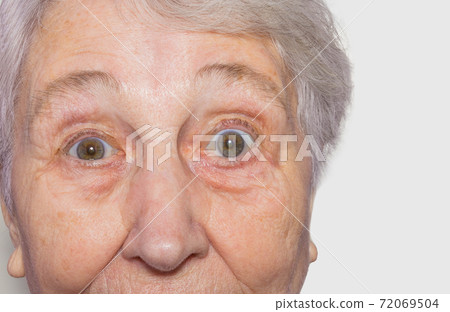 Close up view of senior woman's face on white background Close up view of senior woman's face on white background 72069504