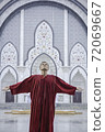 Inspired man in red looking up to the sky with arms outstretched sides 72069667