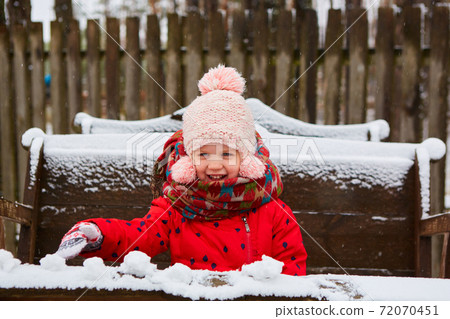 Playful girl has a fun winter time in a snow park. Cute playful girl outdoor enjoying first snow. 72070451