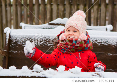 Playful girl has a fun winter time in a snow park. Cute playful girl outdoor enjoying first snow. 72070454