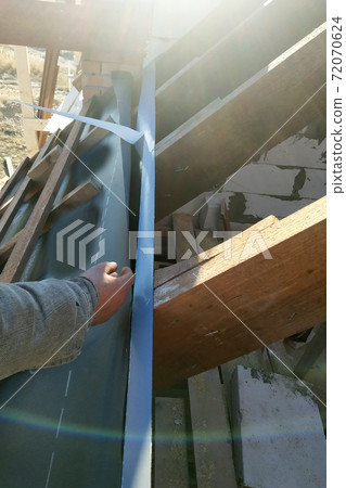 Workers paste adhesive tape on the roof rafters and attach a hydroscope to it 72070624
