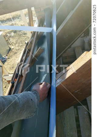 Workers paste adhesive tape on the roof rafters and attach a hydroscope to it Workers paste adhesive tape on the roof rafters and attach a hydroscope to it 72070625