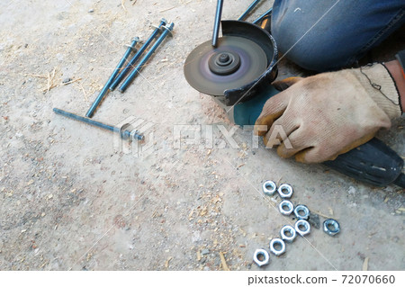 The master cuts and bolts the bolts using an angle grinder The master cuts and bolts the bolts using an angle grinder 72070660