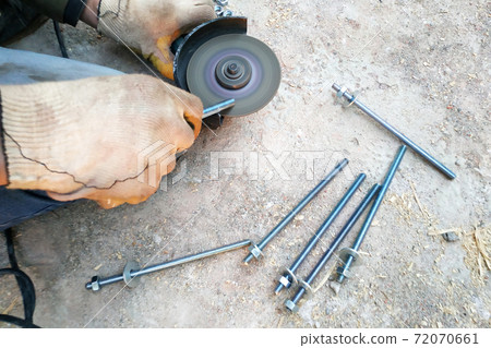 The master cuts and bolts the bolts using an angle grinder The master cuts and bolts the bolts using an angle grinder 72070661
