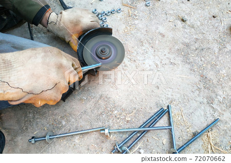 The master cuts and bolts the bolts using an angle grinder The master cuts and bolts the bolts using an angle grinder 72070662