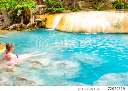 Young woman swims in emerald blue lake, Erawan National park, Thailand Young woman swims in emerald blue lake, Erawan National park, Thailand 72070839