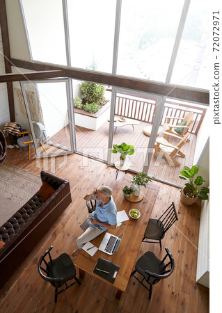 Vertical shot of a middle aged caucasian businessman talking by mobile phone while working remotely at his modern apartment, top view Vertical shot of a middle aged caucasian businessman talking by mobile phone while working remotely at his modern apartment, top view 72072971