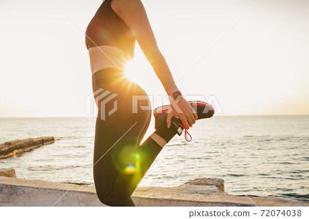 Fitness woman profile stretching at sunrise near the sea Fitness woman profile stretching at sunrise near the sea 72074038